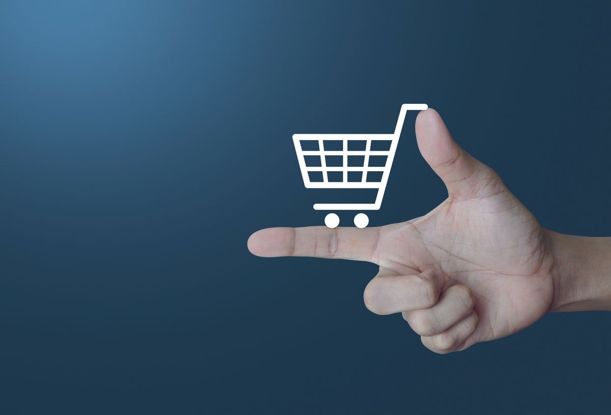 Shopping cart icon on finger over light gradient blue background, Shop online concept